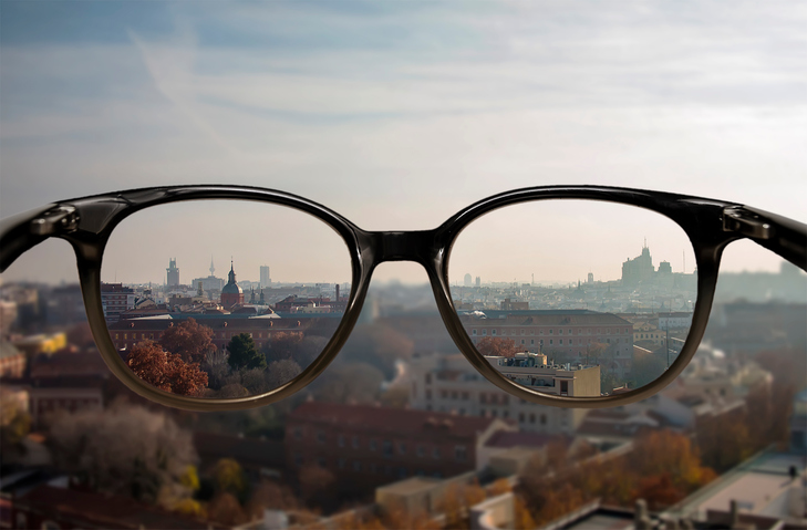 Myopia - neostré videnie do diaľky - rozmazaná kulisa mesta a okuliare s ostrým videním