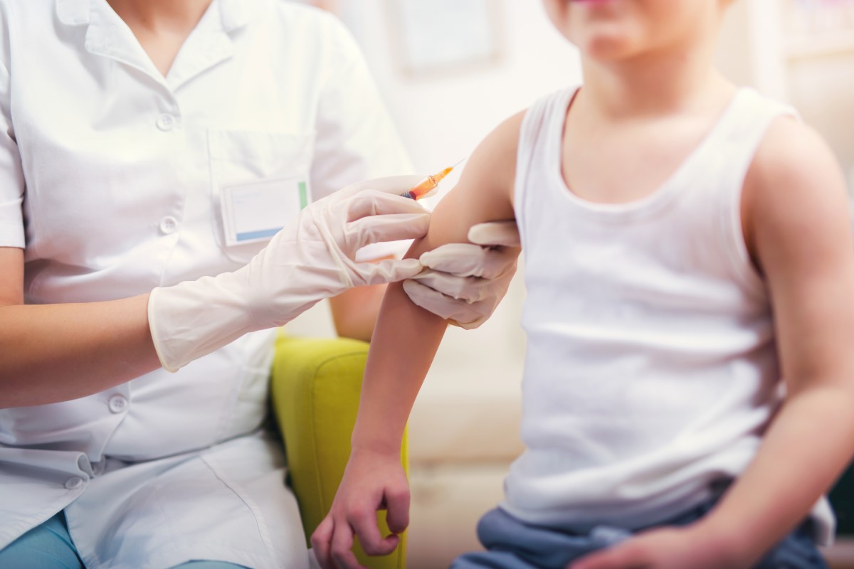 Vakcinácia dieťaťa - lekár očkuje dieťa - dieťa sedí a lekár mu podáva injekciu do ramena