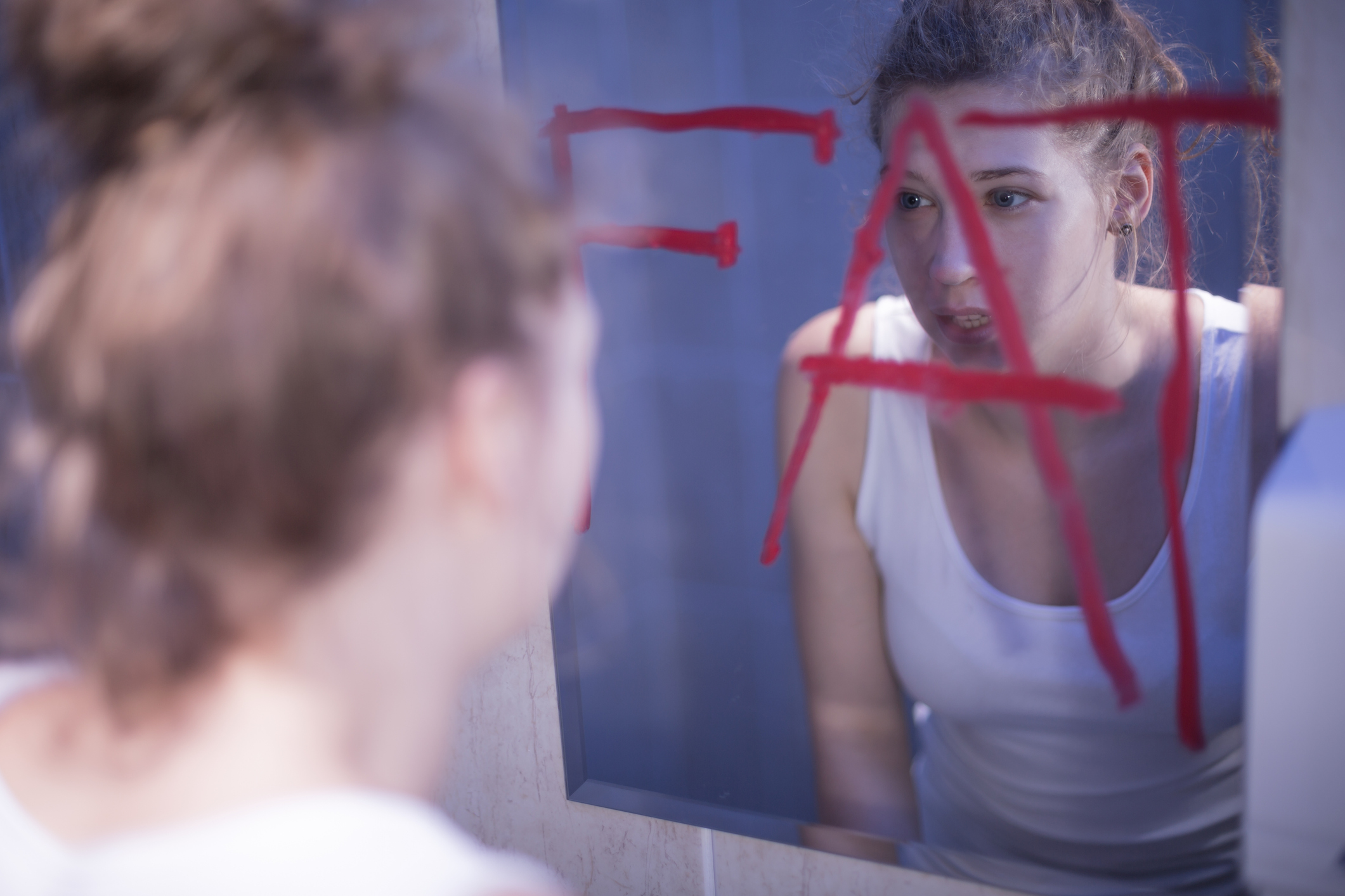 Mladá žena, ktorá sa pri pohľade do zrkadla vidí ako tučná