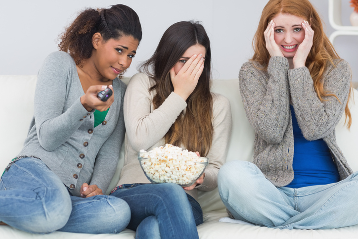 Tri dievčatá majú strach, pozerajú strašidelný film, pukance v miske