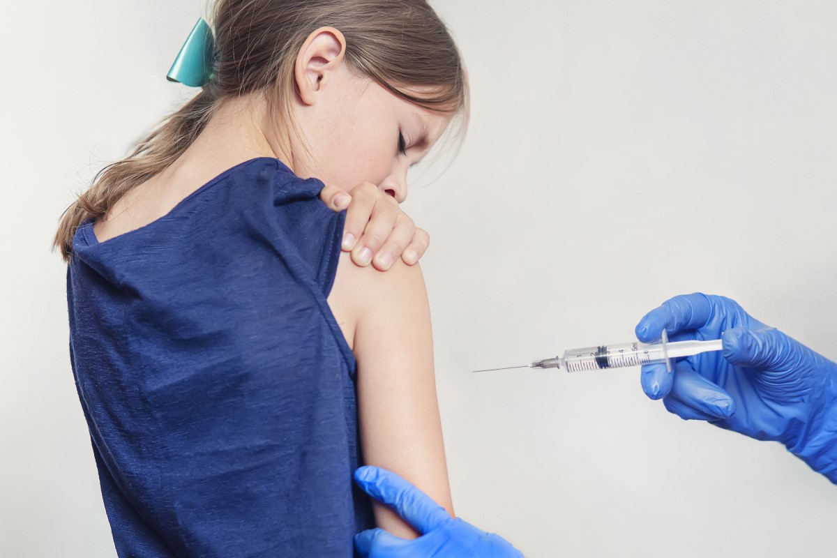 Očkovanie dieťaťa - dievčaťa - lekár pichá vakcínu do ramena