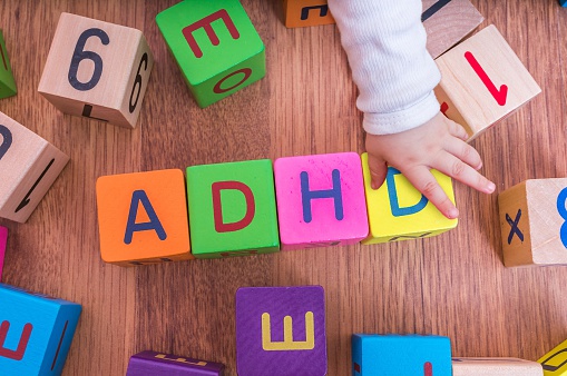 detské kocky s písmenkami, poskladané tak, že vytvárajú názov ADHD, pri nich je detská rúčka