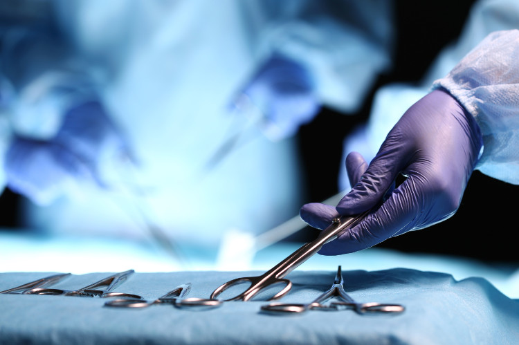 ruka doktora berie peán z operačného stolíka s inštrumentami