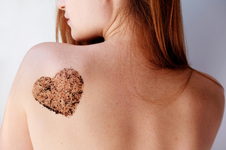 chrbát ženy s peelingom hnedej farby v tvare srdca na jej ľavej lopatke