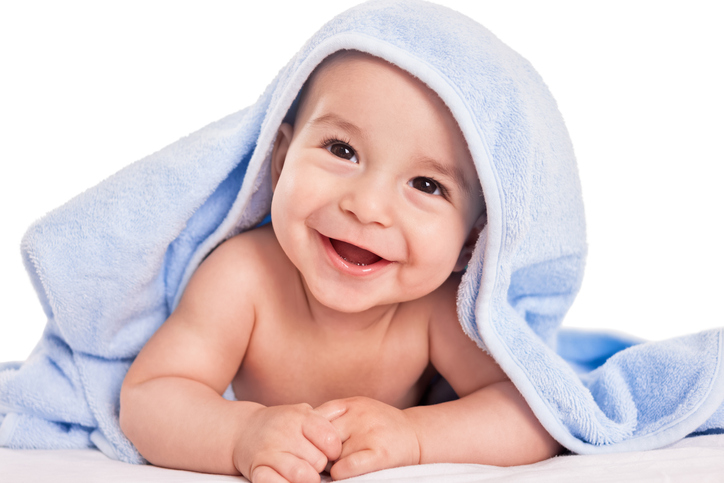 Usmiate dieťa na brušku, prikryté uterákom 