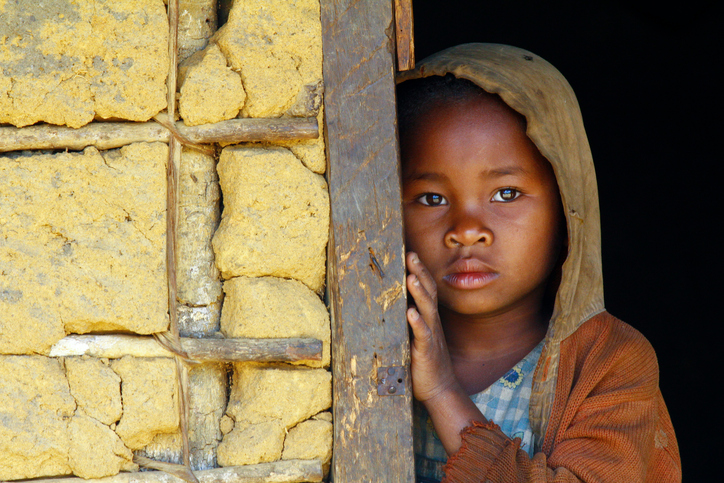 Chudobné černošské dieťa so smutným výrazom tváre v kapucni opreté o múr