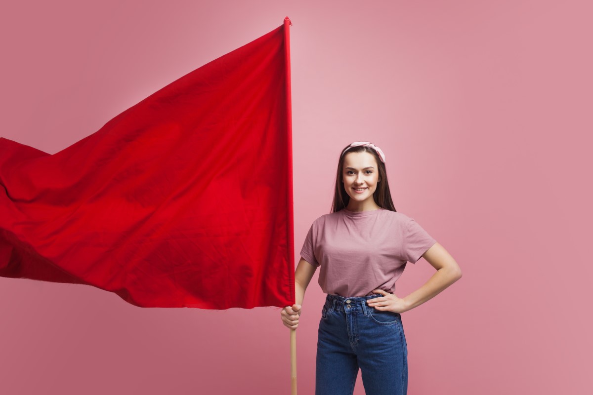 Žena stojí a drží veľkú červenú vlajku, ako výstrahu