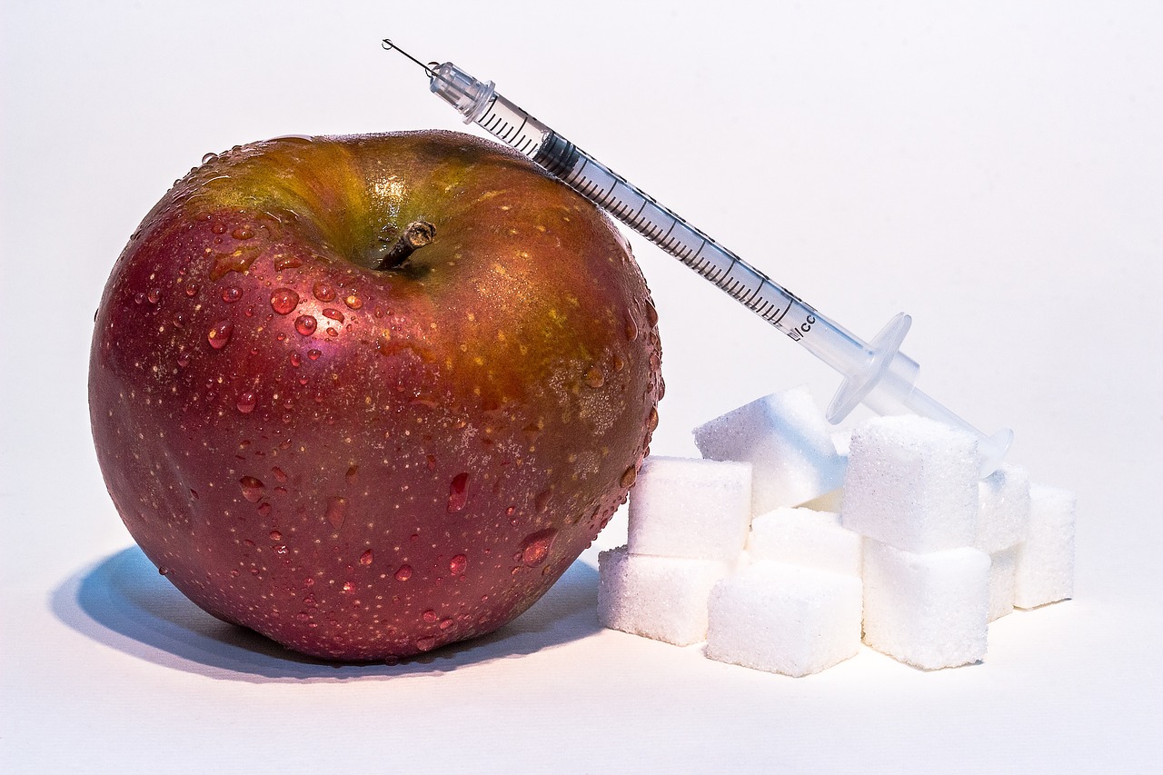 červené jablko, kocky cukru a inzulínová striekačka