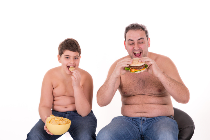 chlapec a otec sa nesprávne stravujú, jedia hamburger, sú obezni