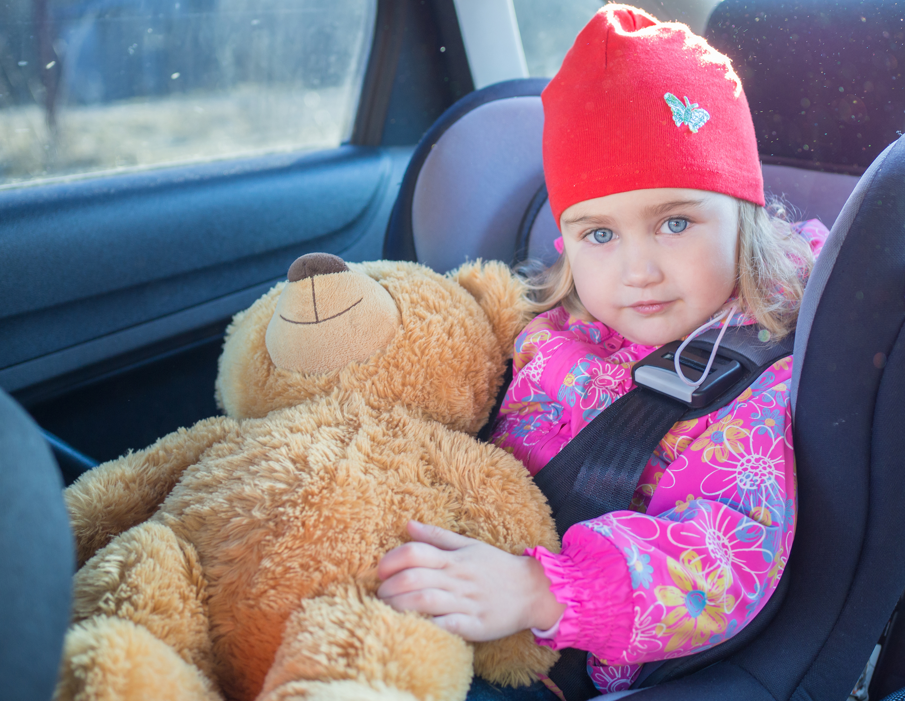 Dieťa v autosedačke, sedí, pozerá sa, spokojný pohľad, drží si plyšového macka