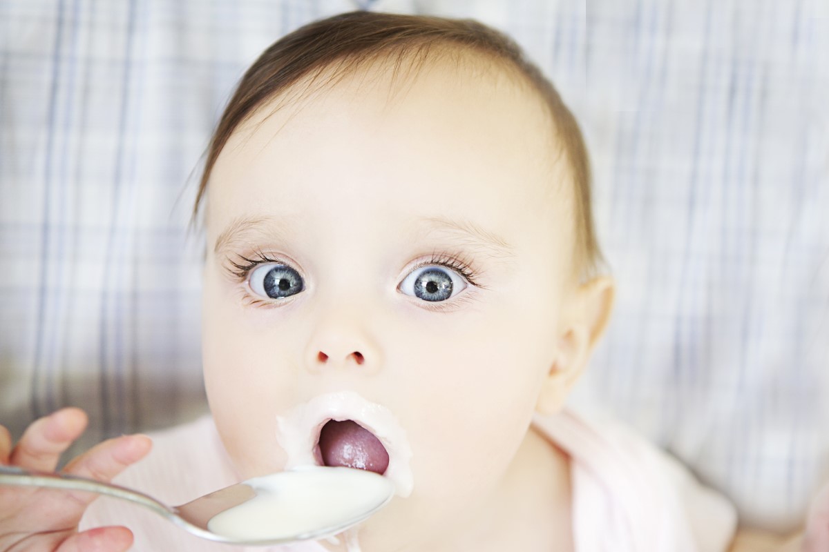 Dieťa s veľkými očami, konzumuje jogurt