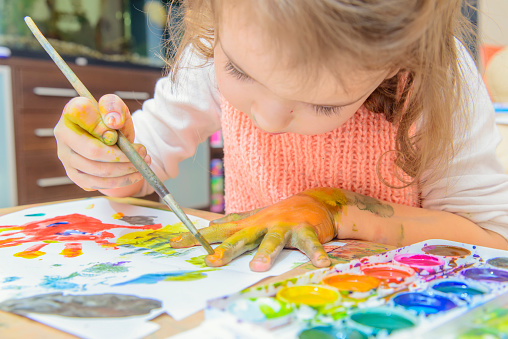 Dievčatko maľuje obrázok vodovými farbami