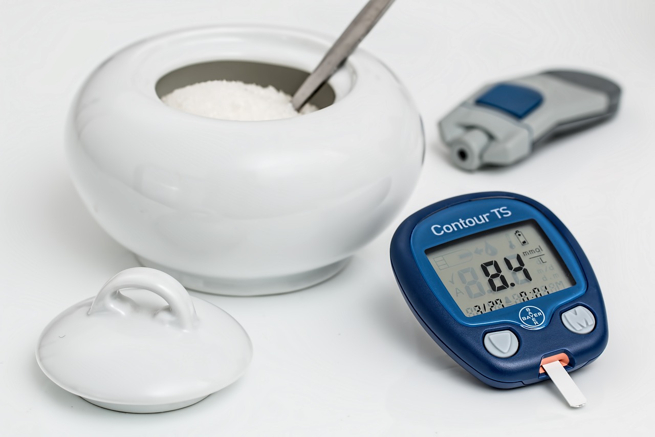 modrý glukomer na stole vedľa nádoby s cukrom