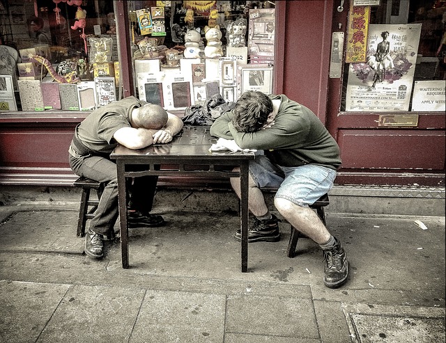 Dvaja muži spia za stolom pred obchodom.Je to starý obchod.  