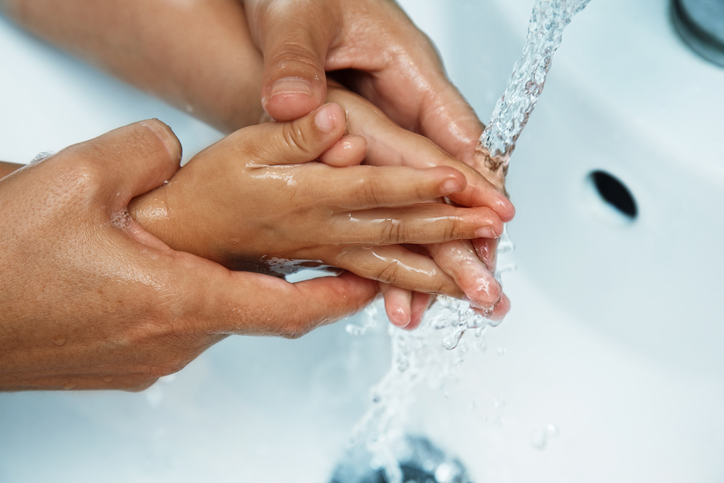 ruky matky nad umývadlom umývajú detské ruky pod tečúcou vodou