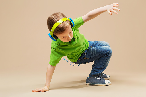 Dieťa v zeleno tričku so slúchatkami na ušiak robí break dance