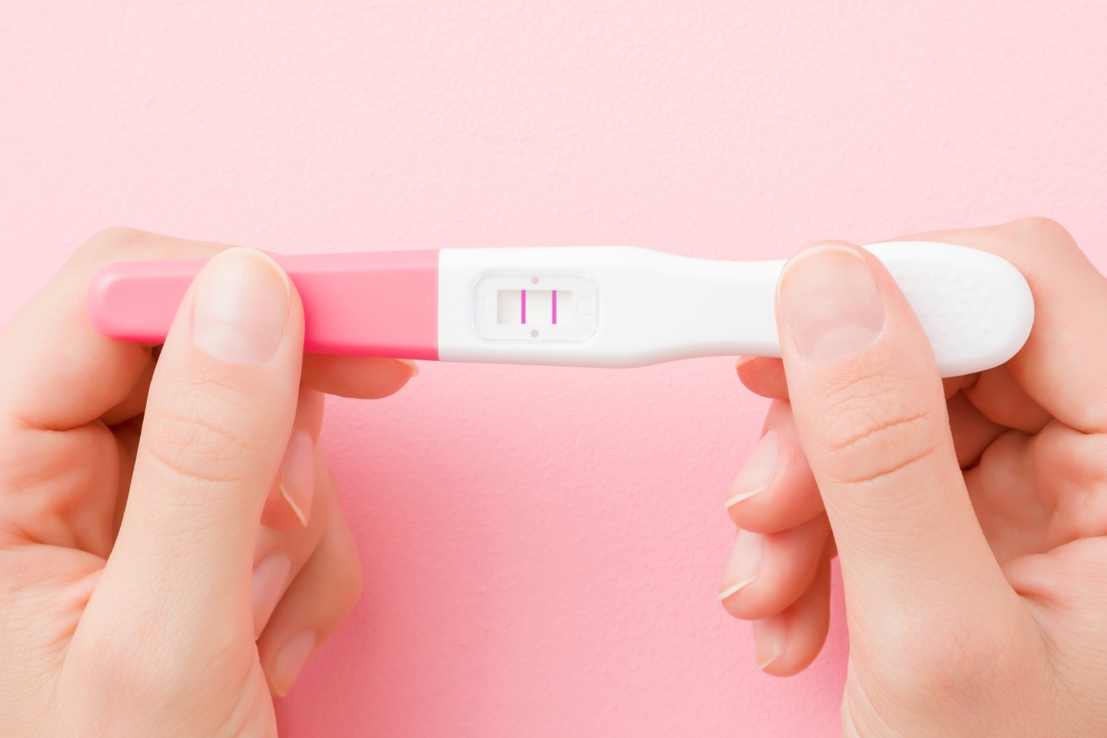 Tehotenský test s pozitívnym výsledkom tehotenstva - žena ho drží v rukách
