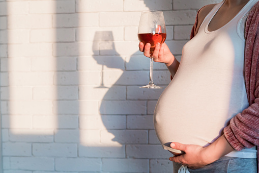 Tehotná žena s pohárom vína v ruke