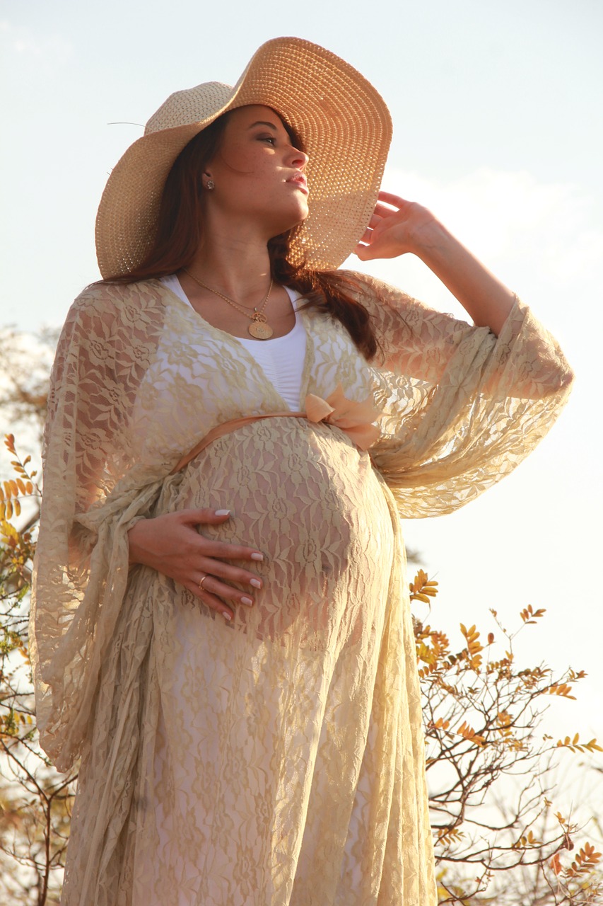 Tehotná žena, oblečené šaty a klobúk