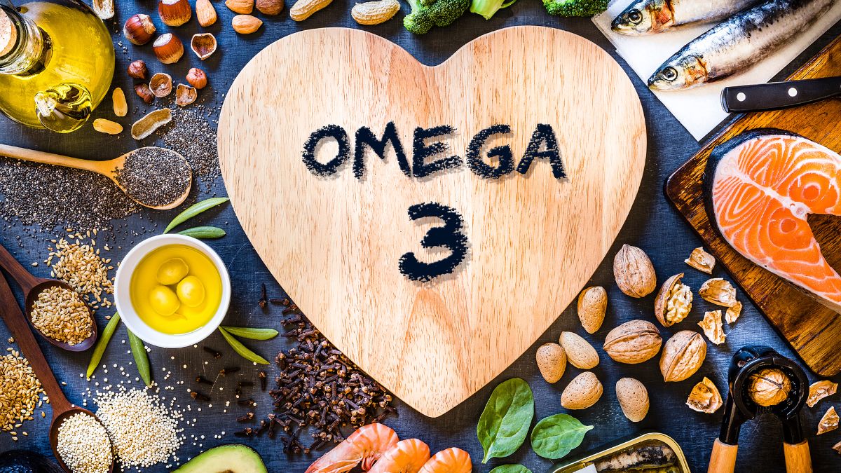 Omega-3 obsahujú najmä kyselinu dokosahexaenovú (DHA), ktorá znižuje riziko prepuknutia Alzheimerovej choroby až o 39 %. Zdroj foto: Canva V strede obrázku je srdce z nápisom Omega 3. Ryby, olivy, olivový olej, orechy, semienka sú rozmiestnené okolo. Aj iné potraviny obsahujúce omega 3 mastné kyseliny.