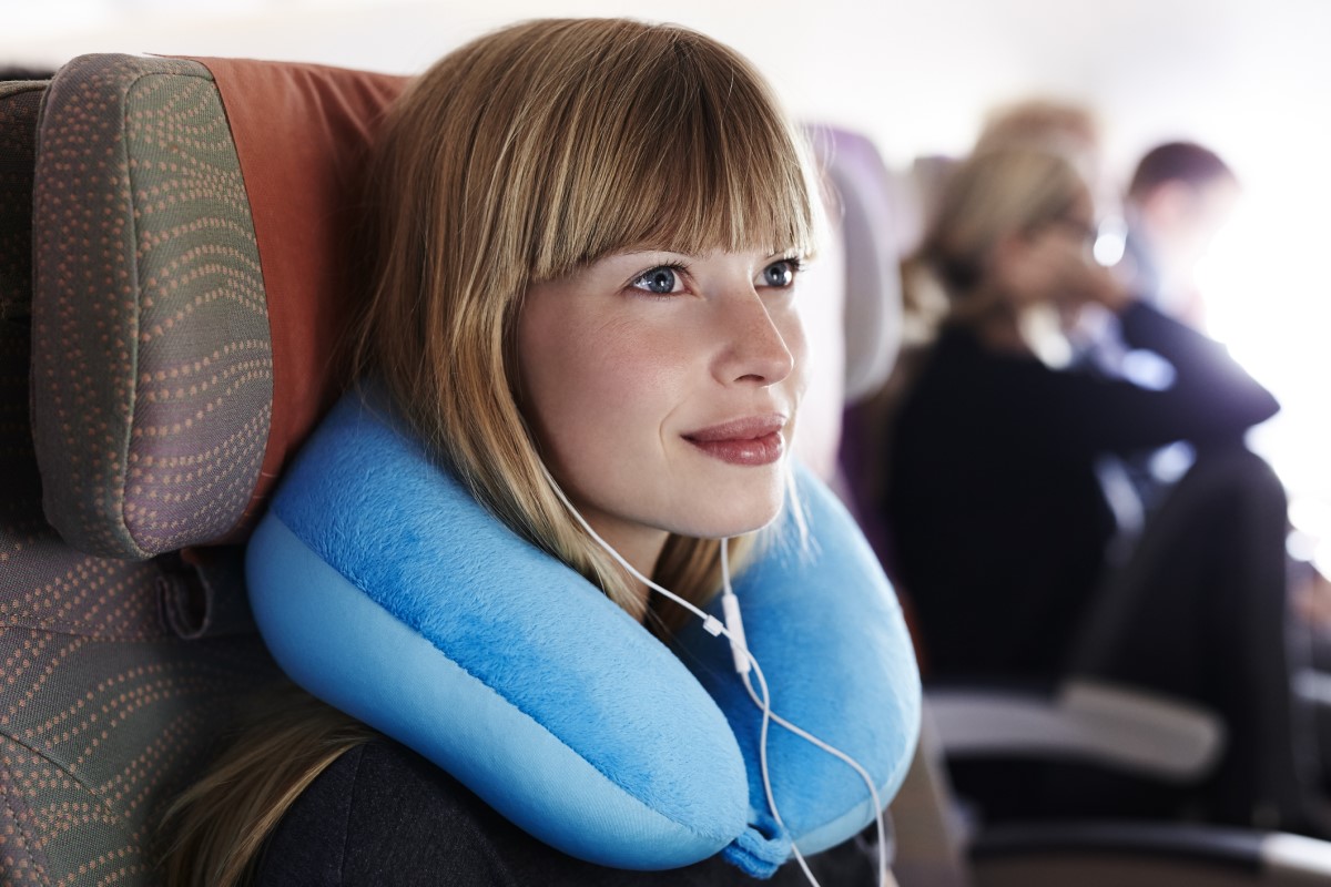 Žena používa pri cestovaní cestovný vankúš okolo krku ako oporu krku a prevenciu bolesti
