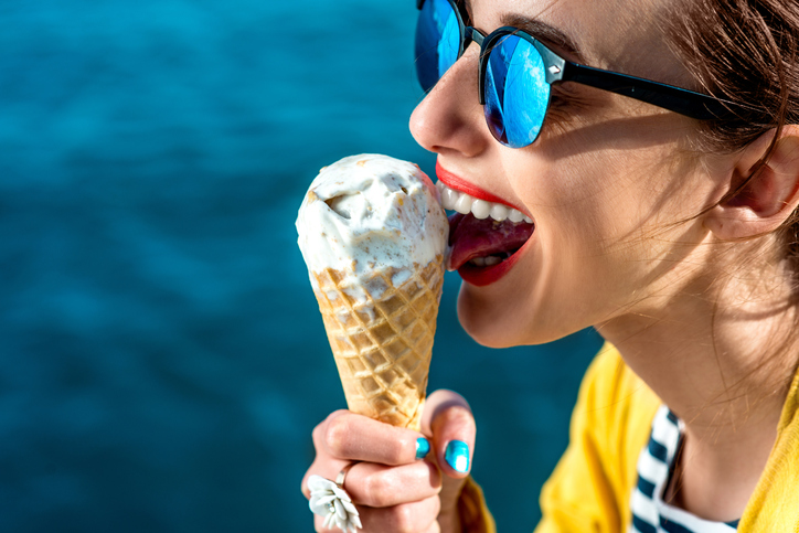 žena v slnečných okuliaroch líže zmrzlinu vedĺa vody