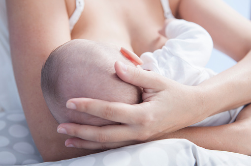 Dojčenie, matka drží dieťa v náručí