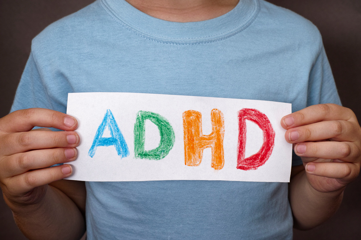 Chlapec drží tabuľku s farebným nápisom ADHD