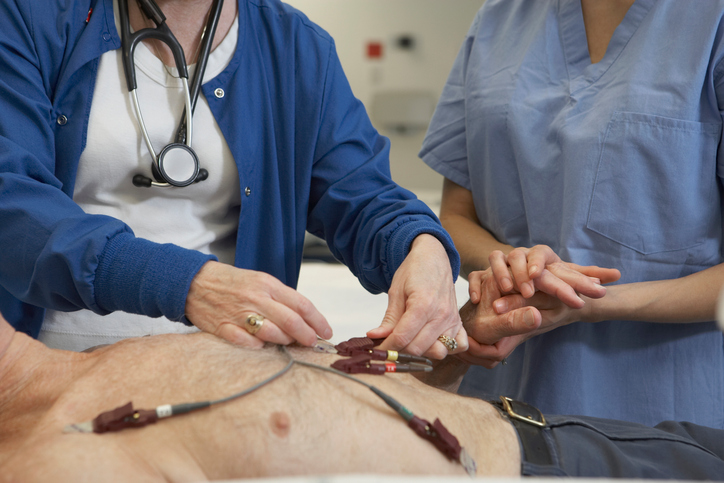 EKG vyšetrenie muža, elektródy na hrudníku, vyšetrujú ho dve lekárky