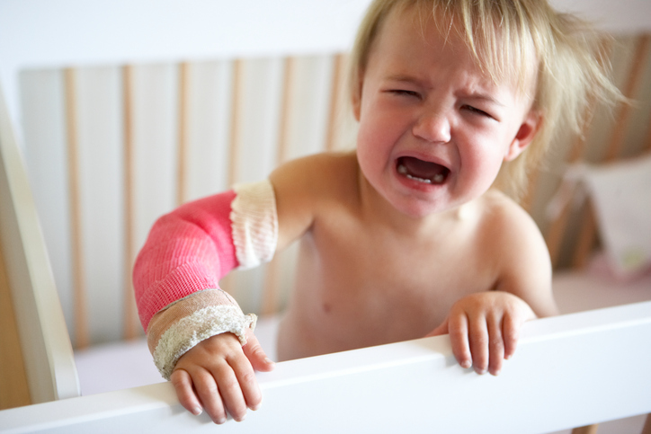The child is crying, has pain in the upper limb, due to a forearm fracture, the upper limb is fixed in a cast.