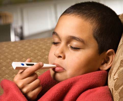 Dieťa si meria telesnú teplotu digitálnym teplomerom v ústach
