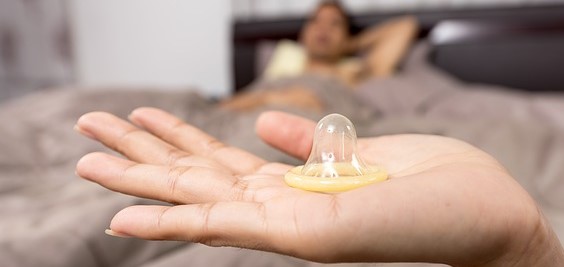 kondóm na žensjek ruke, muž leží v posteli