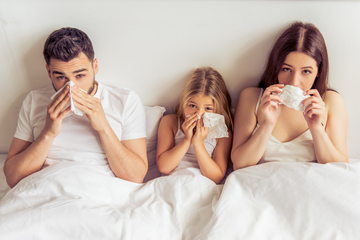 Rodina, teda otec, matka a dcéra ležia v posteli, majú plné nosy, nádchu, pre ochorenie, napríklad chrípku