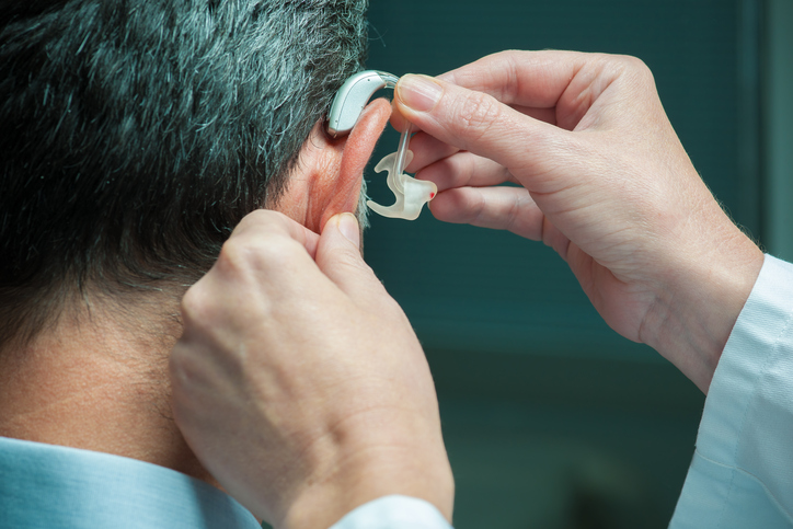 mužovi aplikujú naslúchací aparát na ucho