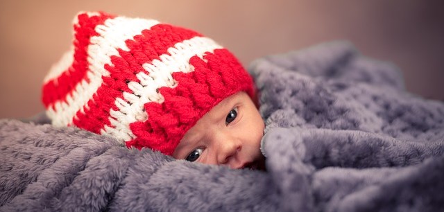 Dieťa, leží zakryté, v červeno bielej pruhovanej čapici
