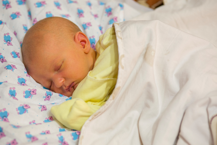Novorodenec, leží v postieľke, oblečený, zakrytý, novorodenecká žltačka, nažltlá koža