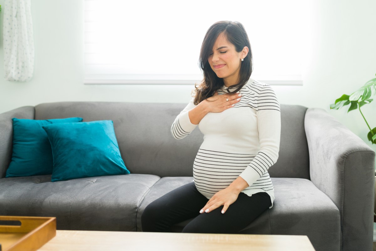 Pálenie záhy je časté u tehotných žien - tehotná žena sedí na sedačke a drží sa za hruď