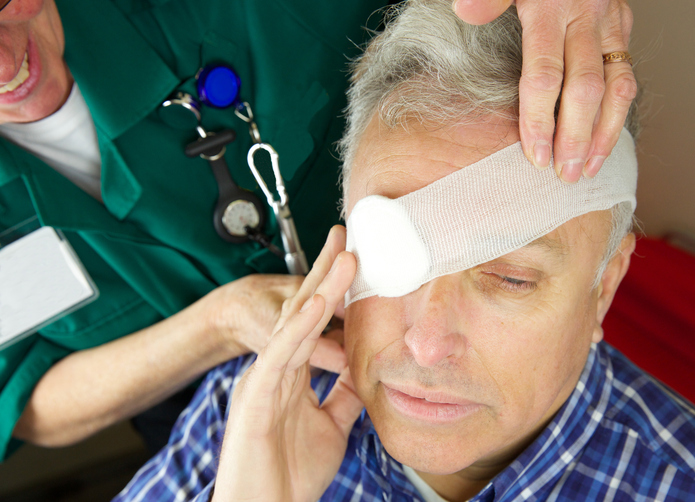 šedivý muý má obviazané oko, napríklad po úraze, ošetruje mu ho zdravotník